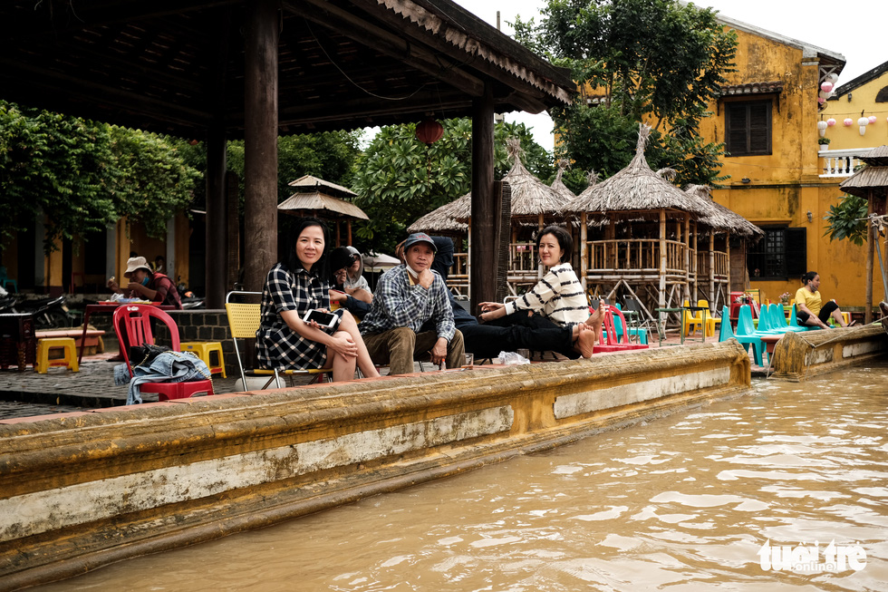 Visitors enjoy drinks at a flooded café in Hoi An Ancient Town, Quang Nam Province, Vietnam, October 24, 2021. Photo: Tan Luc / Tuoi Tre