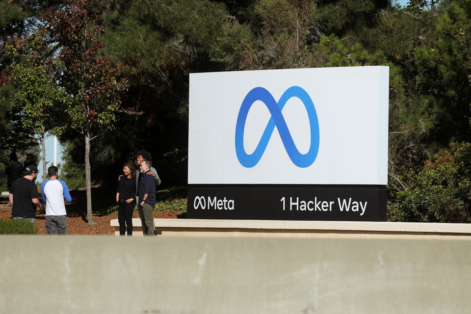 People pose for a photo in front of a sign of Meta, the new name for the company formerly known as Facebook, at its headquarters in Menlo Park, California, U.S. October 28, 2021.