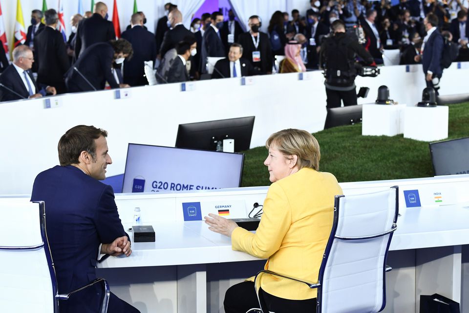 French President Emmanuel Macron speaks with German Chancellor Angela Merkel before the opening session of the G20 leaders summit in Rome, Italy October 30, 2021. Photo: Brendan Smialowski/Pool via Reuters
