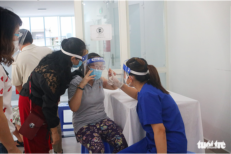 A health worker explains the COVID-19 vaccination procedure to a child with disabilities at the medical center in District 3, Ho Chi Minh City, October 31, 2021. Photo: Thu Hien / Tuoi Tre