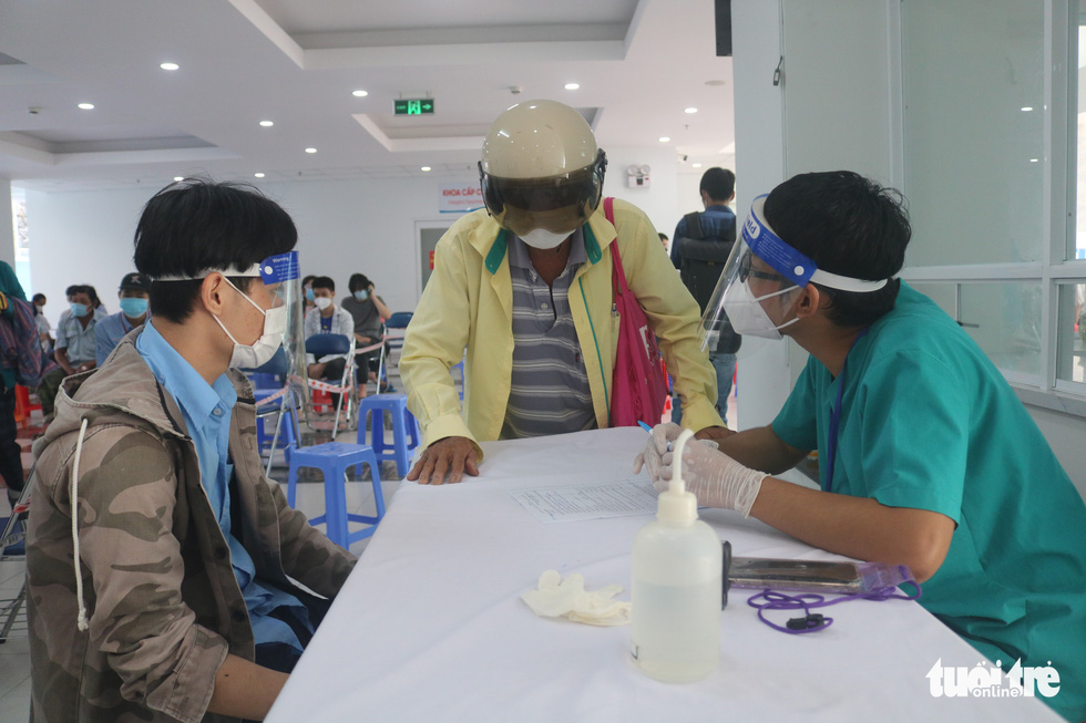 A health worker talks with family members of a child with disabilities during a COVID-19 vaccination session at the medical center in District 3, Ho Chi Minh City, October 31, 2021. Photo: Thu Hien / Tuoi Tre