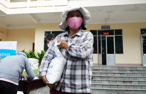 Ha, a Hoi An resident, happily carries a bag of rice she received in exchange for beer cans. Photo: Le Trung / Tuoi Tre