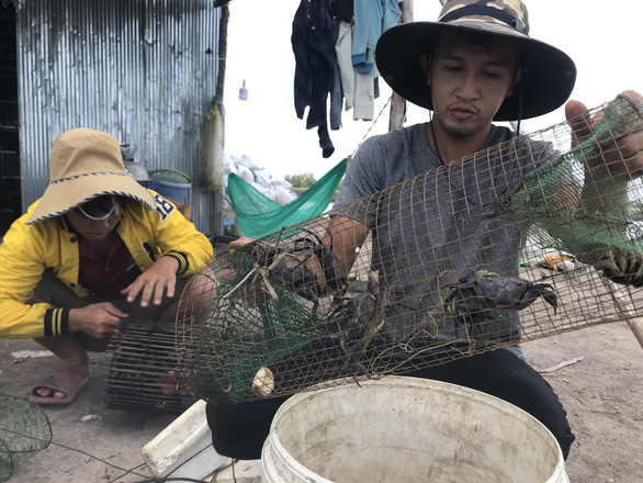 Bui Tri Nhan (right) catches around 100 kilograms of crab and smaller fish each day. Photo: T.Nhon / Tuoi Tre
