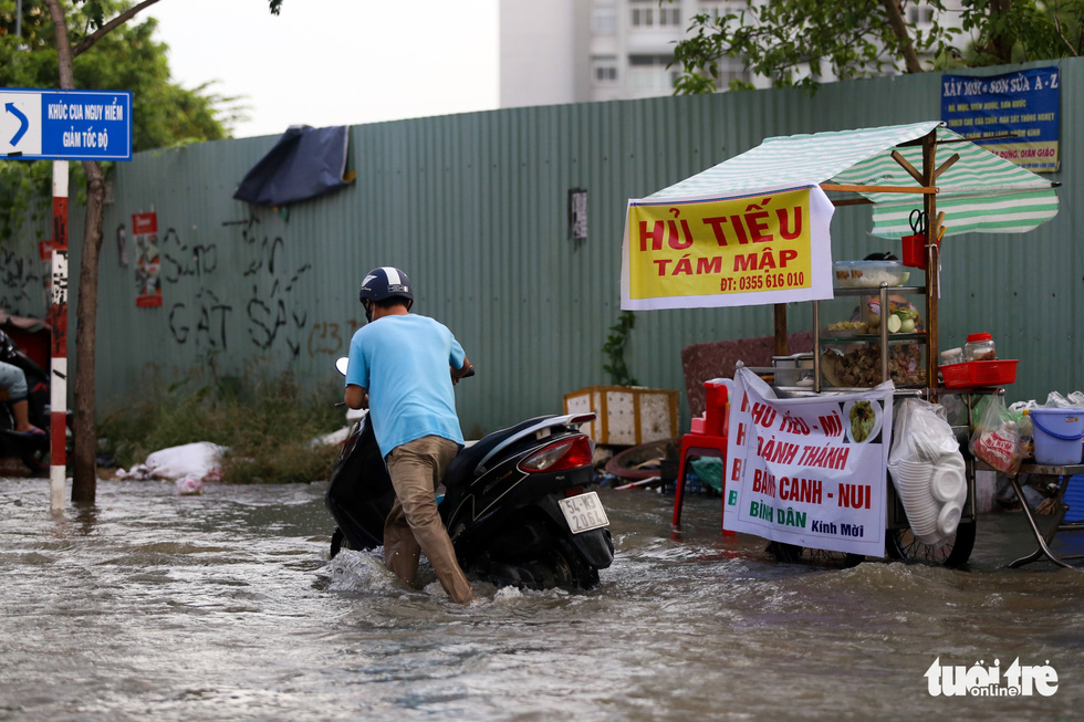 A man pushes his broken-down motorbike on a flooded street in Ho Chi Minh City, November 5, 2021. Photo: Chau Tuan / Tuoi Tre