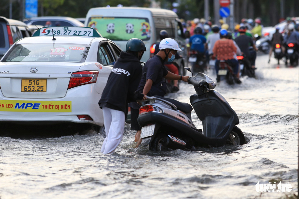 A man helps a woman push her broken-down motorbike on flooded Nguyen Thi Thap Street in District 7, Ho Chi Minh City, November 5, 2021. Photo: Nhat Thinh / Tuoi Tre