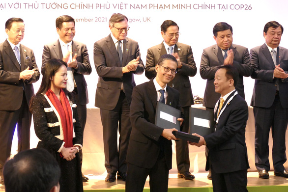 The image shows the exchange of an MoU between Vietnam’s T&T Group chairman Do Quang Hien (right) and the UK’s Standard Chartered representative at a ceremony on November 1, 2021 in Glasgow, Scotland. Photo: Le Kien / Tuoi Tre