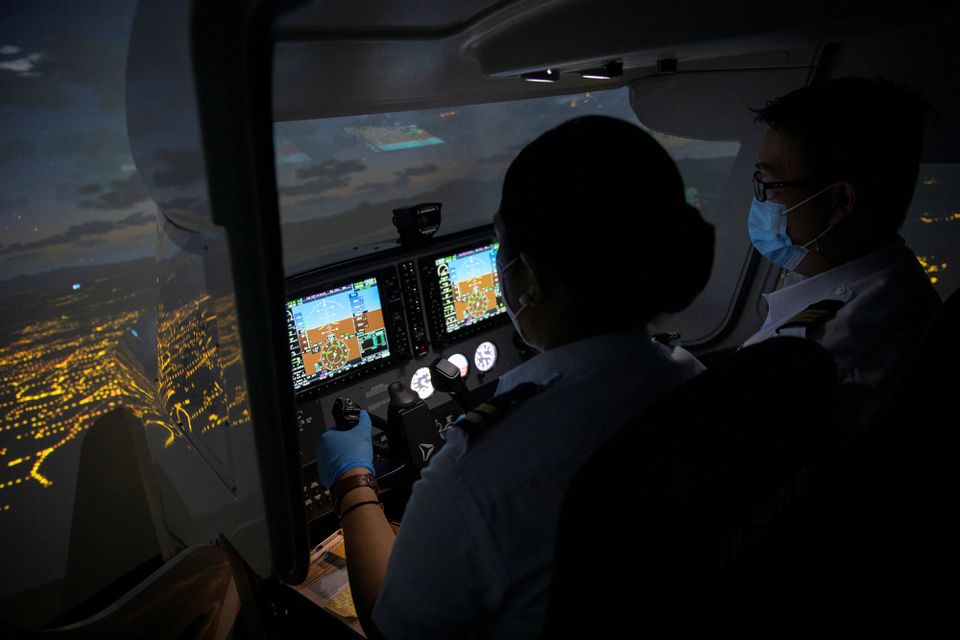 Cadet Casey Abadilla, a flight student, operates a flight simulator beside an instructor, both wearing masks for protection against the coronavirus disease (COVID-19), at the Alpha Aviation Group campus in Clark, Pampanga province, Philippines, November 3, 2021. Photo: Reuters