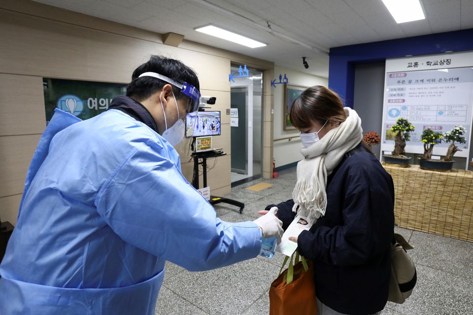 A teacher uses a hand sanitiser to prepare a student arriving for annual College Scholastic Ability Test (CSAT), a nationwide university entrance exam, amid coronavirus disease (COVID-19) outbreak, at a school in Seoul, South Korea November 18, 2021. Photo: Chung Sung-Jun/Pool via Reuters