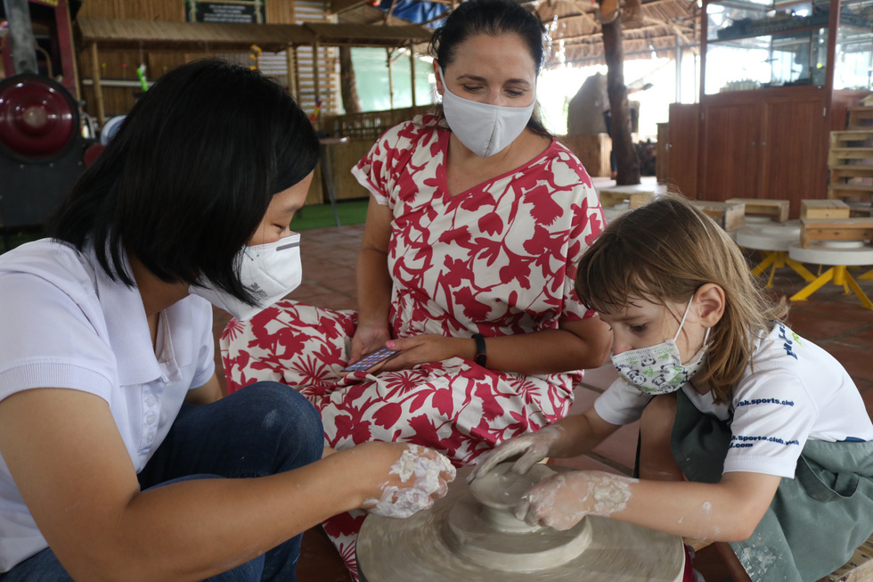 An instructor guides a foreigner and her 5-year-old child on making pottery at Nhan Tri Dung pottery workshop in District 7, Ho Chi Minh City. Photo: Ngoc Phuong – Hoang An / Tuoi Tre.
