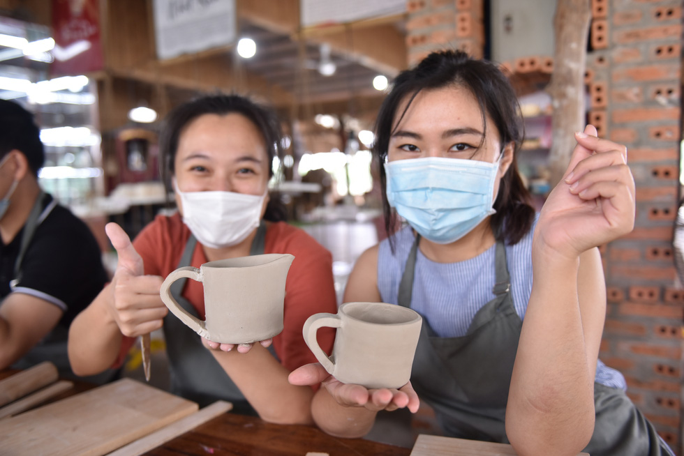 Tran Ngoc Lan and her friend show off their finished pottery at Nhan Tri Dung pottery workshop in District 7, Ho Chi Minh City. Photo: Ngoc Phuong – Hoang An / Tuoi Tre.