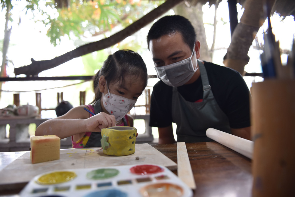 A father and child paint a clay cup at the Nhan Tri Dung pottery workshop in District 7, Ho Chi Minh City. Photo: Ngoc Phuong – Hoang An / Tuoi Tre.