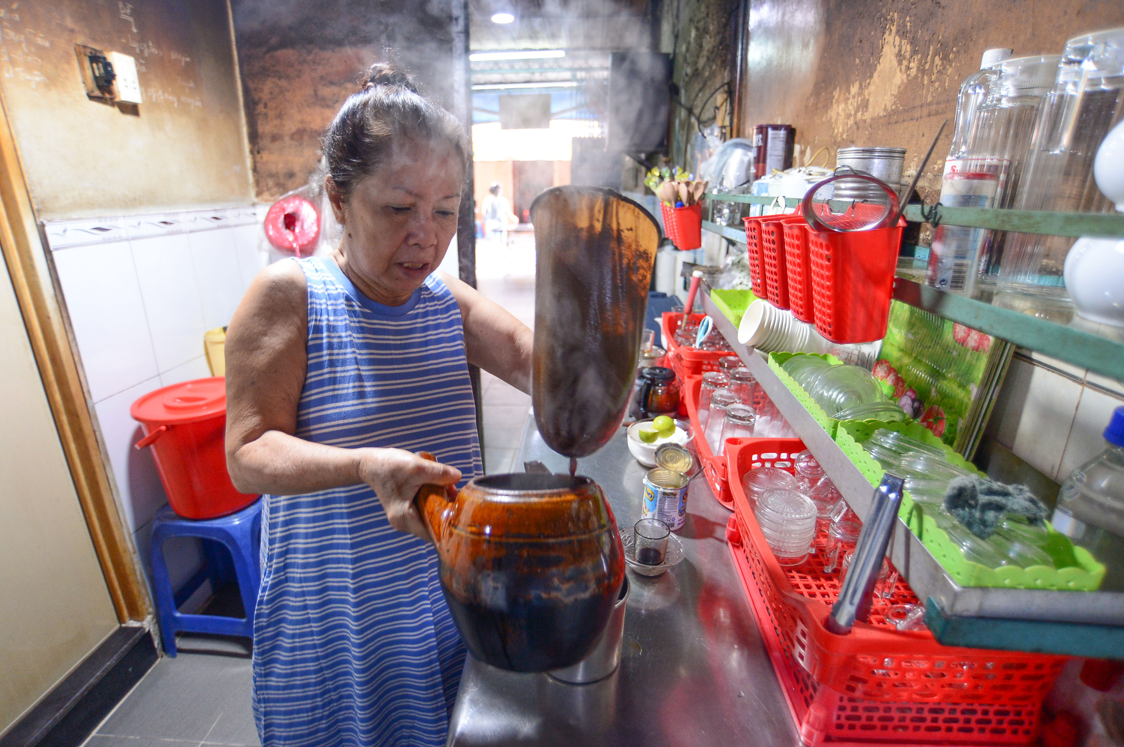 Nguyen Thi Suong, owner of Cheo Leo Café, makes coffee using a cloth filter and clay pot at her shop in District 3 in Ho Chi Minh City. Photo: Quang Dinh / Tuoi Tre