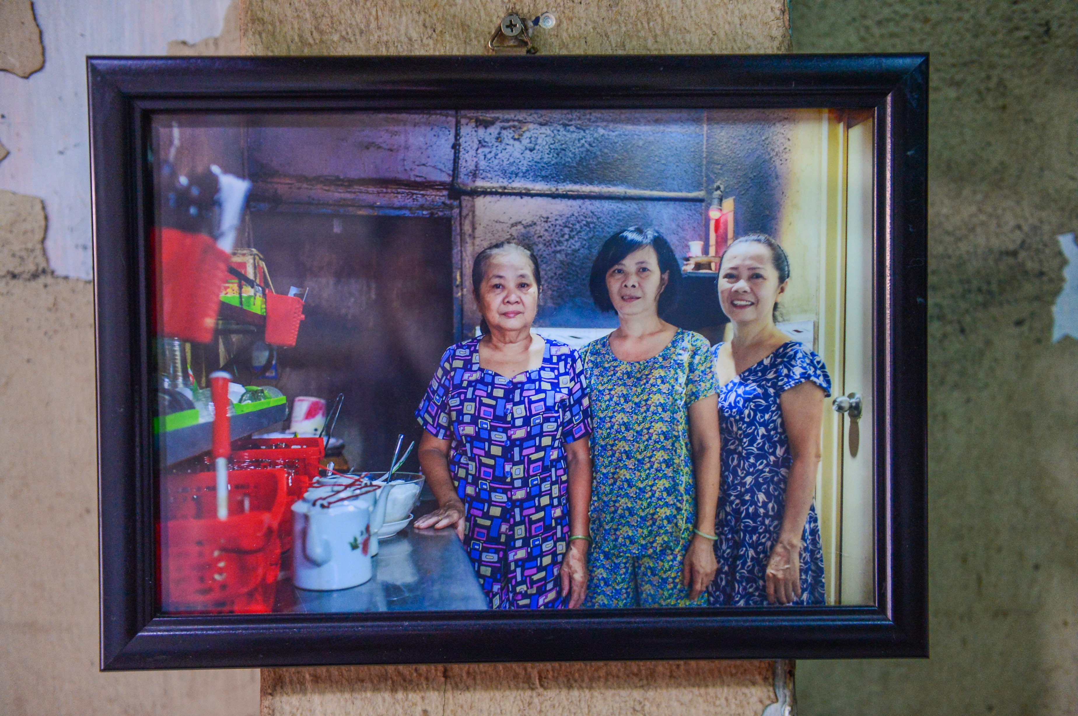 A framed photo of Suong (right) and her sisters who have run their family’s coffee shop together for decades hangs on the wall at Cheo Leo Cafe in District 3 in Ho Chi Minh City. Photo: Quang Dinh / Tuoi Tre