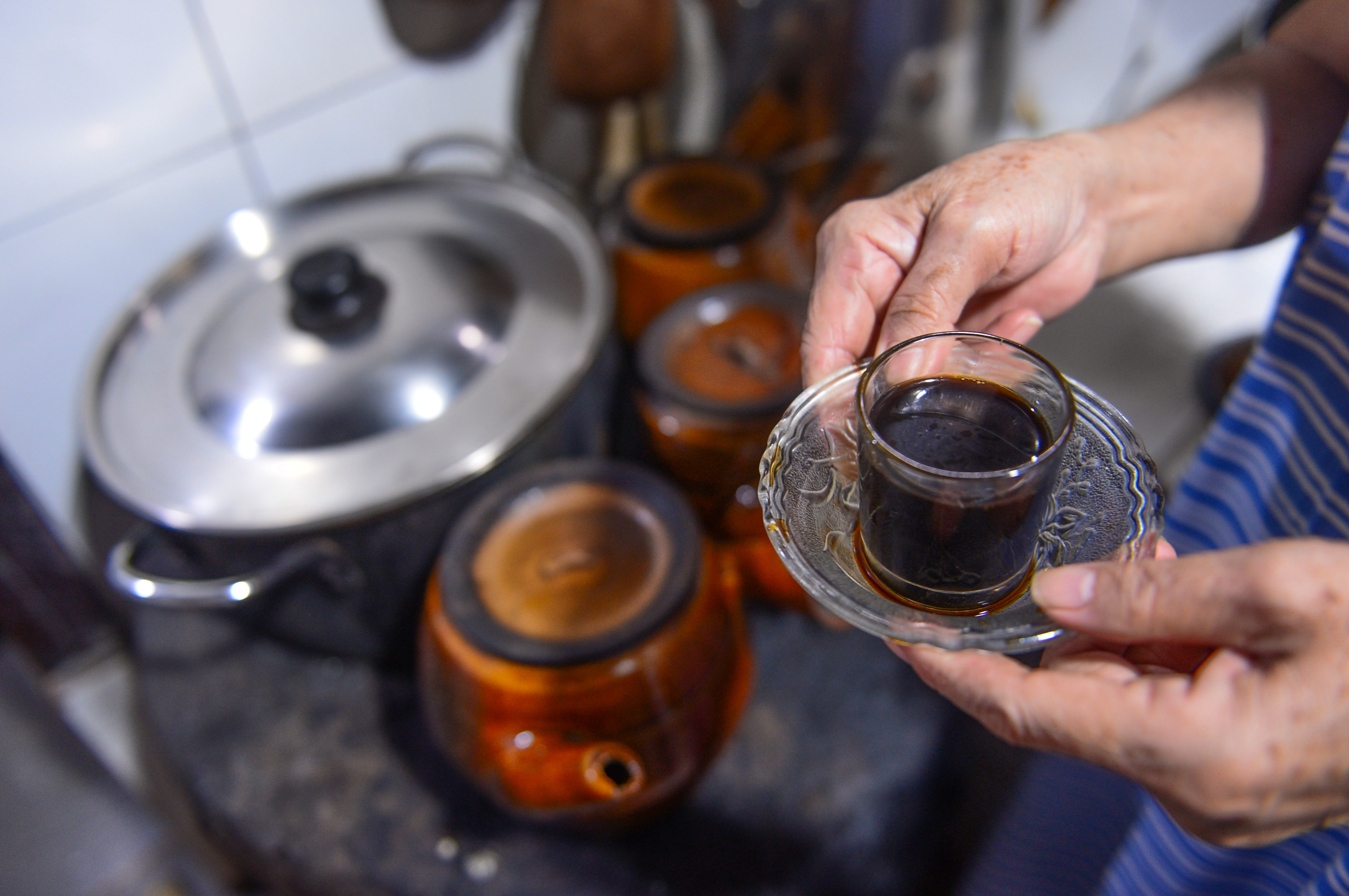 A glass of hot coffee poured from clay pots put over a charcoal brazier which Suong’s father built over 80 years ago at Cheo Leo Cafe in District 3 in Ho Chi Minh City. Photo: Quang Dinh / Tuoi Tre