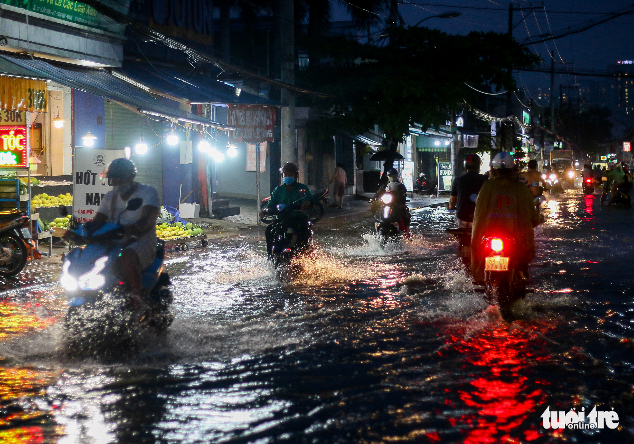 Commuters travel on a flooded street in Nha Be District, Ho Chi Minh City, November 20, 2021. Photo: Chau Tuan / Tuoi Tre