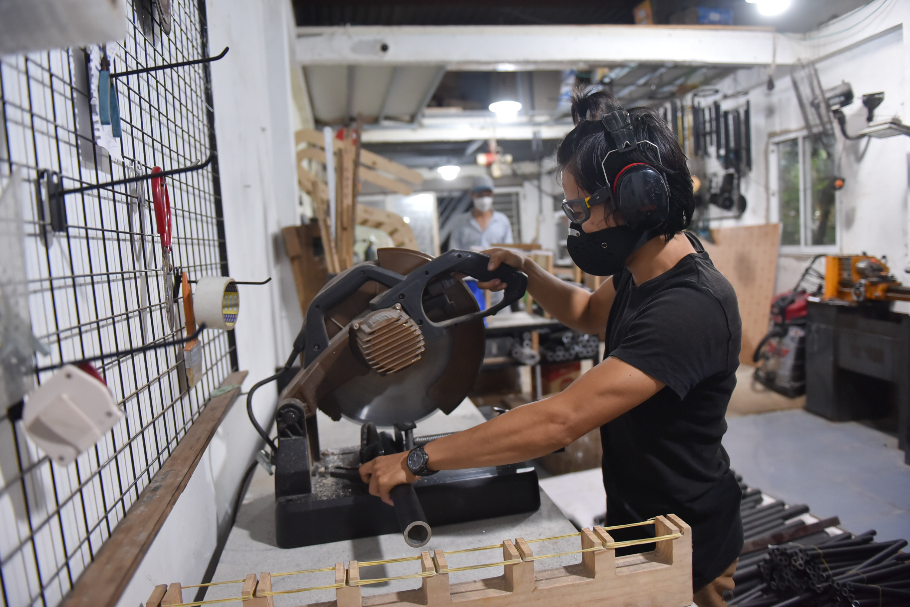 Tran Ngoc Hong Duc cuts a tube to create a set of wind chimes at his workshop in Binh Thanh District in Ho Chi Minh City. Photo: Ngoc Phuong / Tuoi Tre News