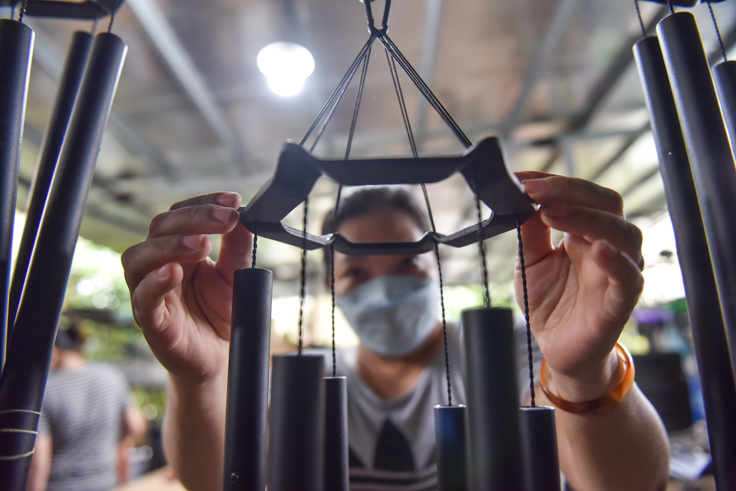 A staff member puts the top circle on to complete a set of wind chimes. Photo: Ngoc Phuong / Tuoi Tre News