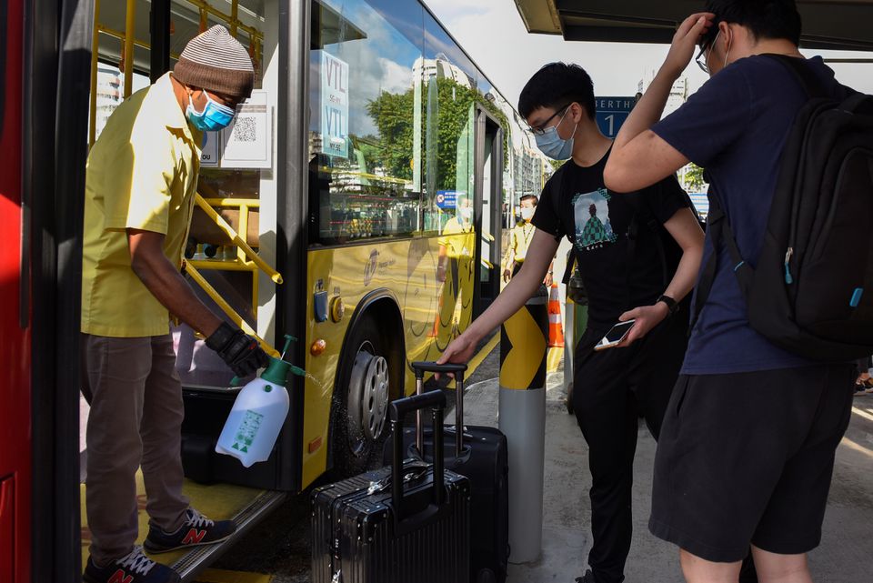A bus driver sprays disinfectant on the luggage of passengers travelling to Malaysia as the Vaccinated Travel Lane between Singapore and Malaysia opens after the land border between the two countries reopened following nearly two years of being shut down due to the coronavirus disease (COVID-19) pandemic, at a bus station in Singapore November 29, 2021. Photo: Reuters