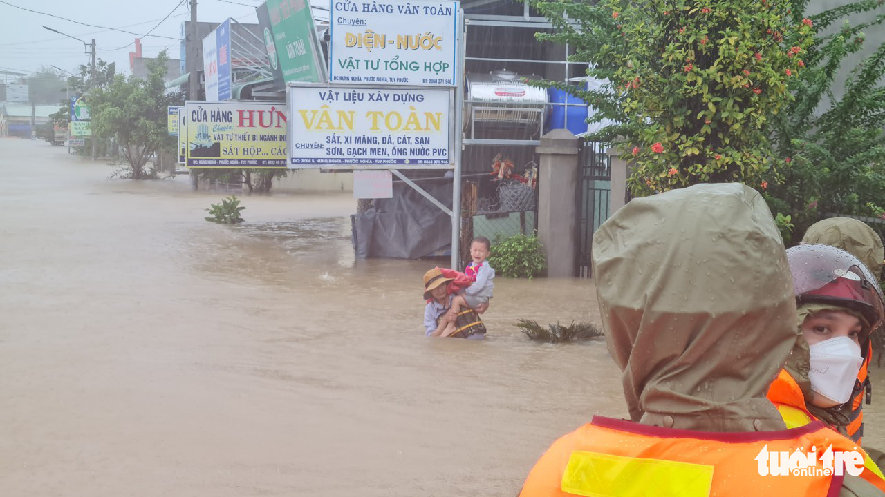 A man carries his son on a flooded street in Binh Dinh Province, November 30, 2021. Photo: Lam Thien / Tuoi Tre
