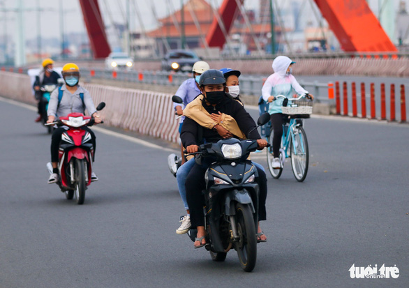 A passenger hugs a motorcyclist on a street in Ho Chi Minh City, December 4, 2021. Photo: Chau Tuan / Tuoi Tre