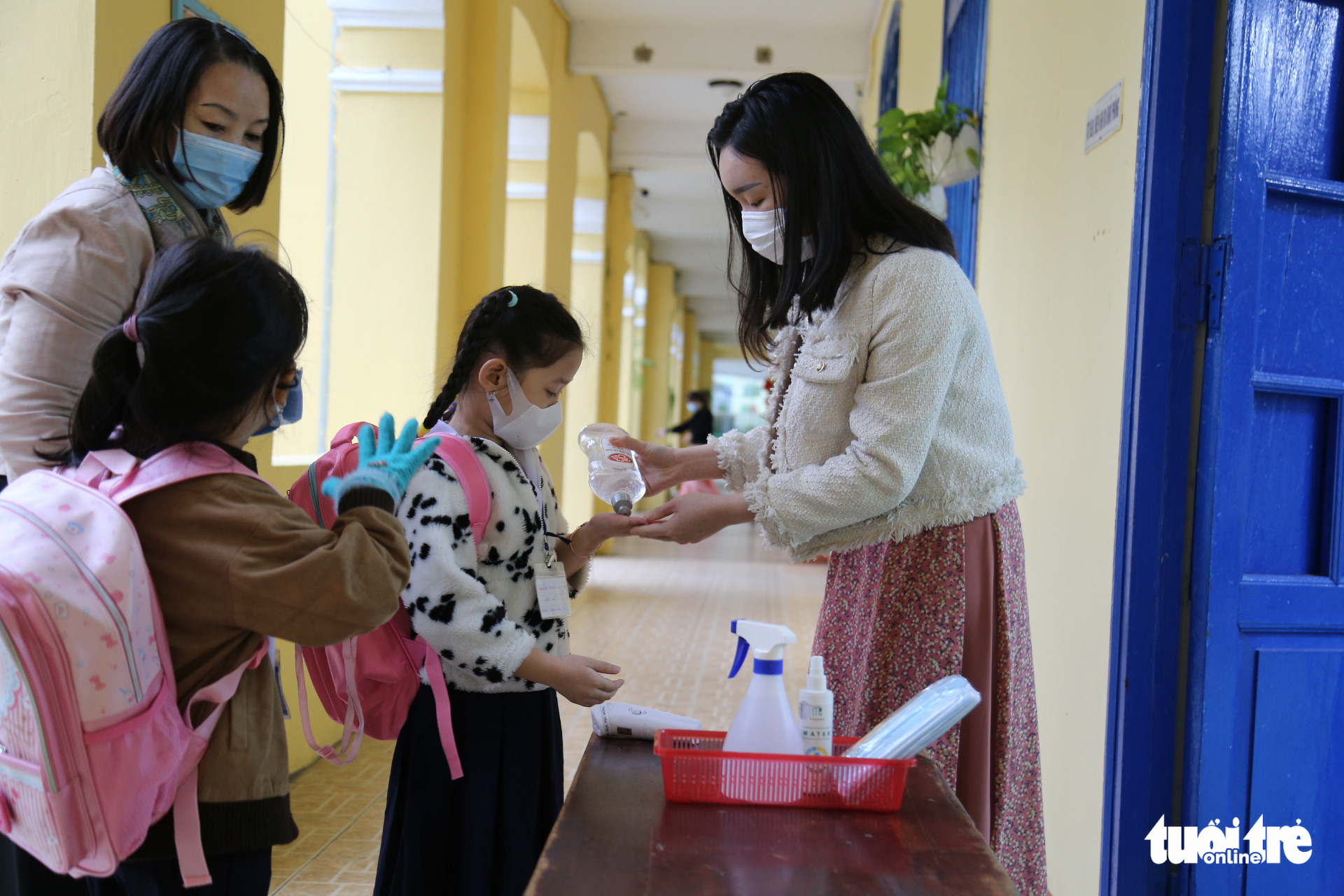 A teacher helps first graders use hand sanitizer at Phu Dong Elementary School in Hai Chau District, Da Nang City, December 6, 2021. Photo: Tuoi Tre