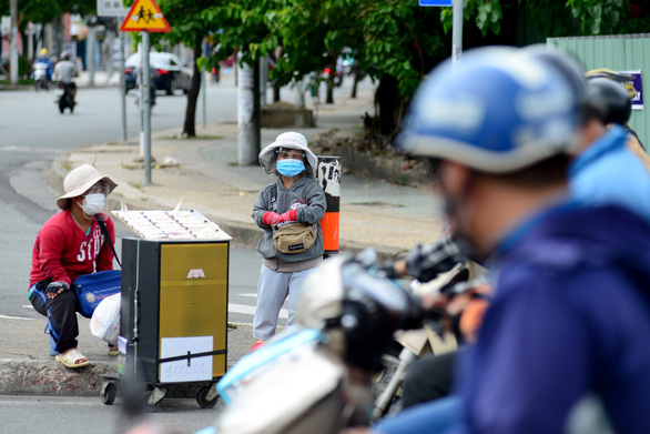 Nguyen Van Luong and his wife, with masks and droplet shields on, offer lottery tickets for sale to passers-by in Ho Chi Minh City. Photo: Le Van / Tuoi Tre
