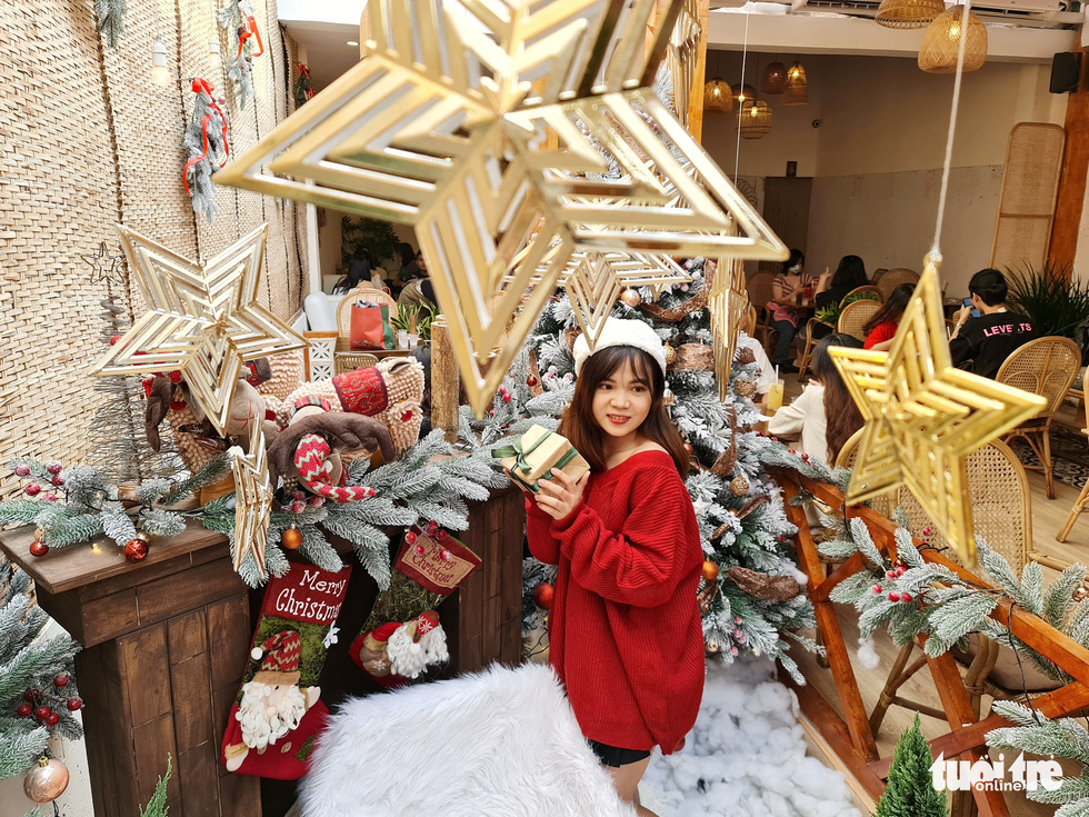 A young woman holds Christmas ornaments to take photos at a coffee shop in Tan Dinh Ward, District 1. Photo: Cong Trieu / Tuoi Tre