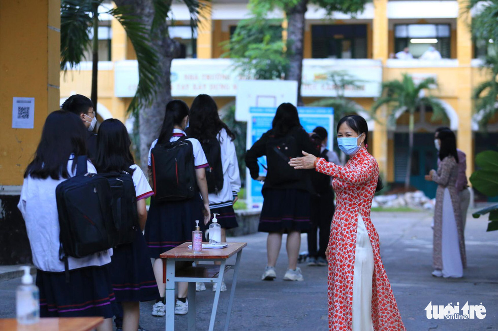 A teacher at Trung Vuong Senior High School in District 1, Ho Chi Minh City is seen guiding students to stand in line for body temperature check upon entering the school. Photo: Nhat Thinh / Tuoi Tre