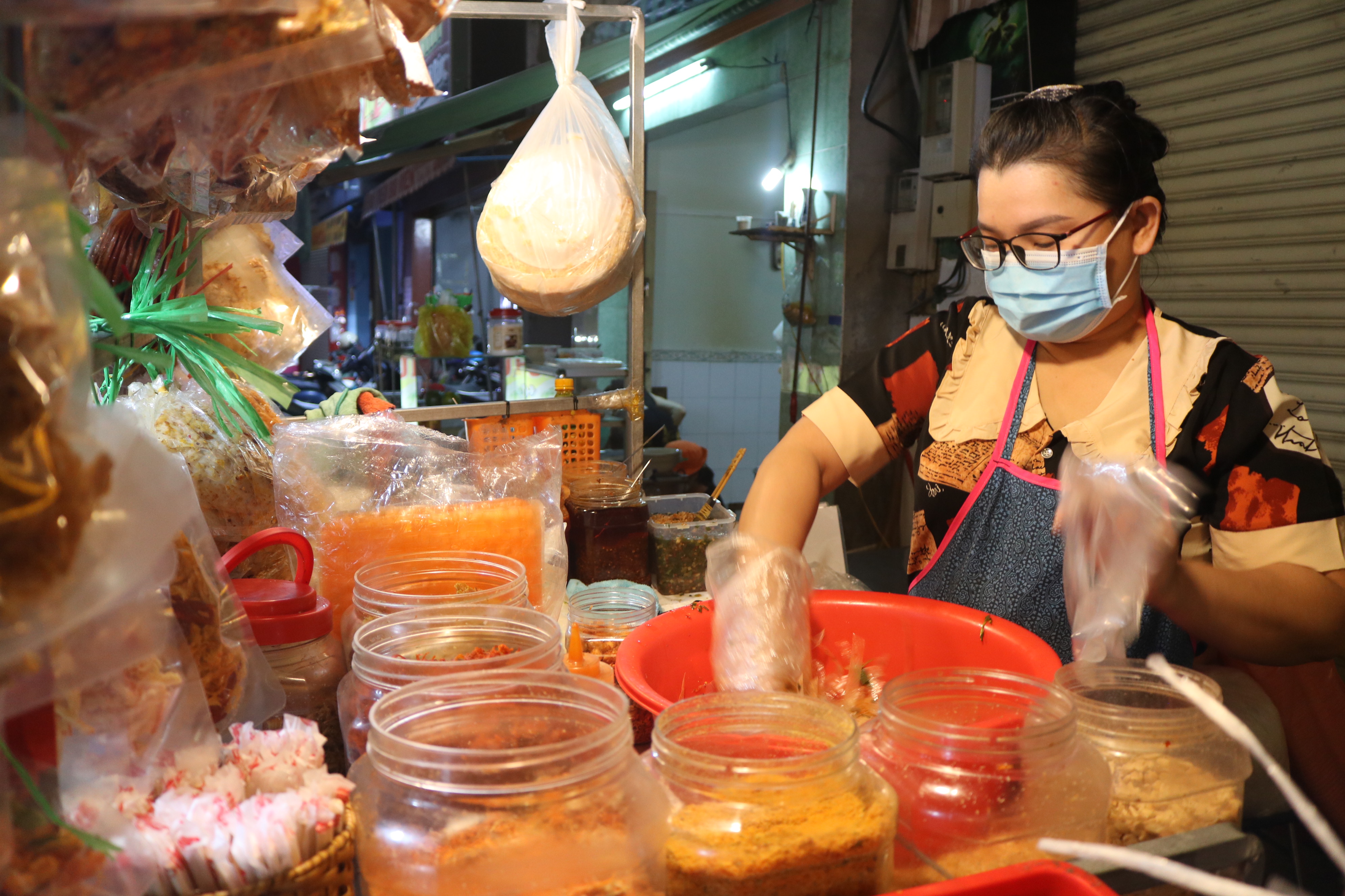A street vendor wear plastic gloves while giving a mix to her 'banh trang tron' at a stall in Thu Duc City in Ho Chi Minh City on December 15, 2021. Photo: Hoang An / Tuoi Tre News