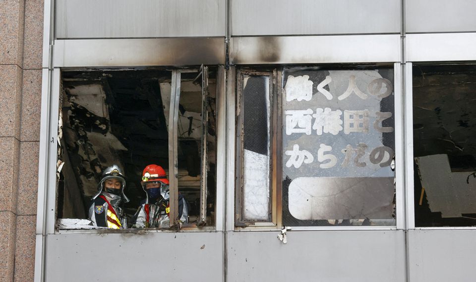 Firefighters are seen at a building where a fire broke out in Osaka, western Japan December 17, 2021 in this photo taken by Kyodo. Kyodo/via Reuters