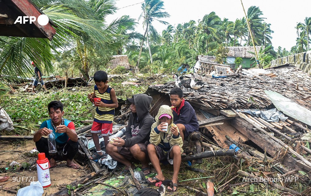 Residents gather by a collapsed house in Hernani town, Eastern Samar province on December 17, 2021. Photo: AFP