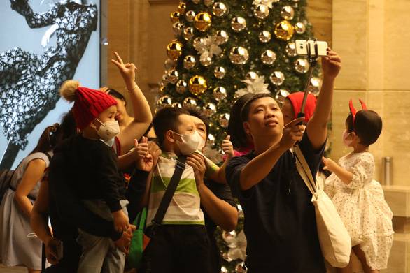 A family is taking photos in front of a Christmas-themed backdrop. Photo: Hoang An / Tuoi Tre