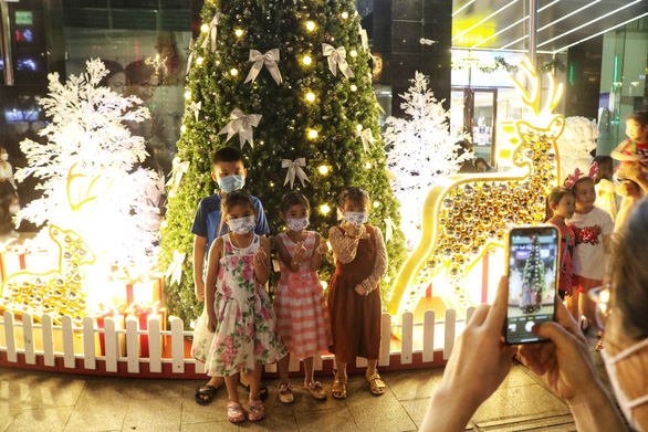 Four children are posing for a photo in front of a Christmas-themed backdrop at Nguyen Hue pedestrian street, Ho Chi Minh City. Photo: Hoang An / Tuoi Tre