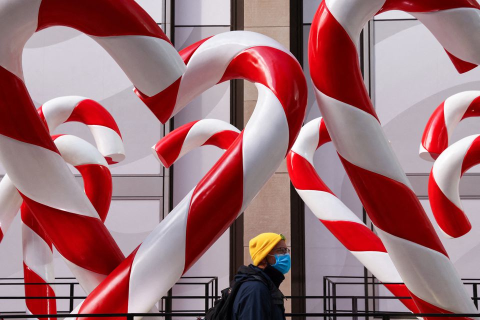 A person in a face mask walks by holiday decorations on Sixth Avenue as the Omicron coronavirus variant continues to spread in Manhattan, New York City, U.S., December 19, 2021. Photo: Reuters