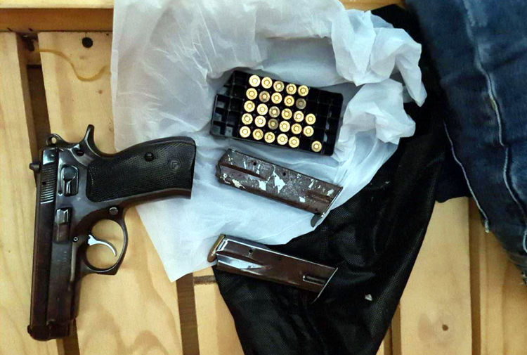 A gun and bullets belonging to the gang are confiscated by officers in this supplied photo.