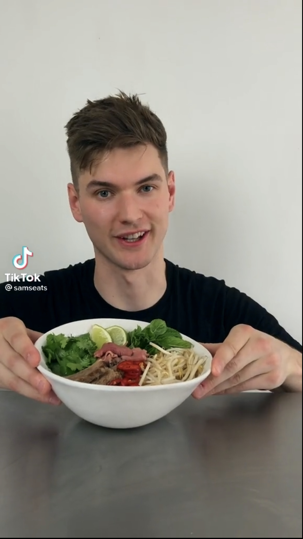 A screenshot shows Sam Way holding a bowl of Vietnamese pho he cooks in a video on his @samseats TikTok channel.