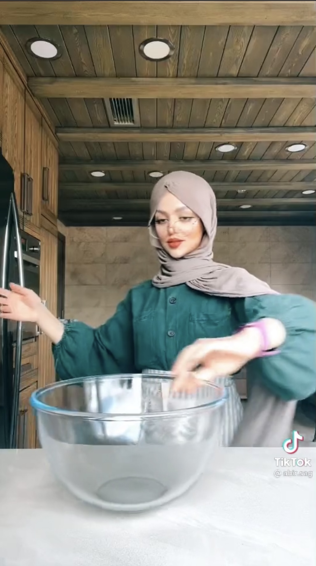A screenshot shows Abir Saghir preparing utensils to make pho-style noodles in a video on her @abir.sag TikTok channel.
