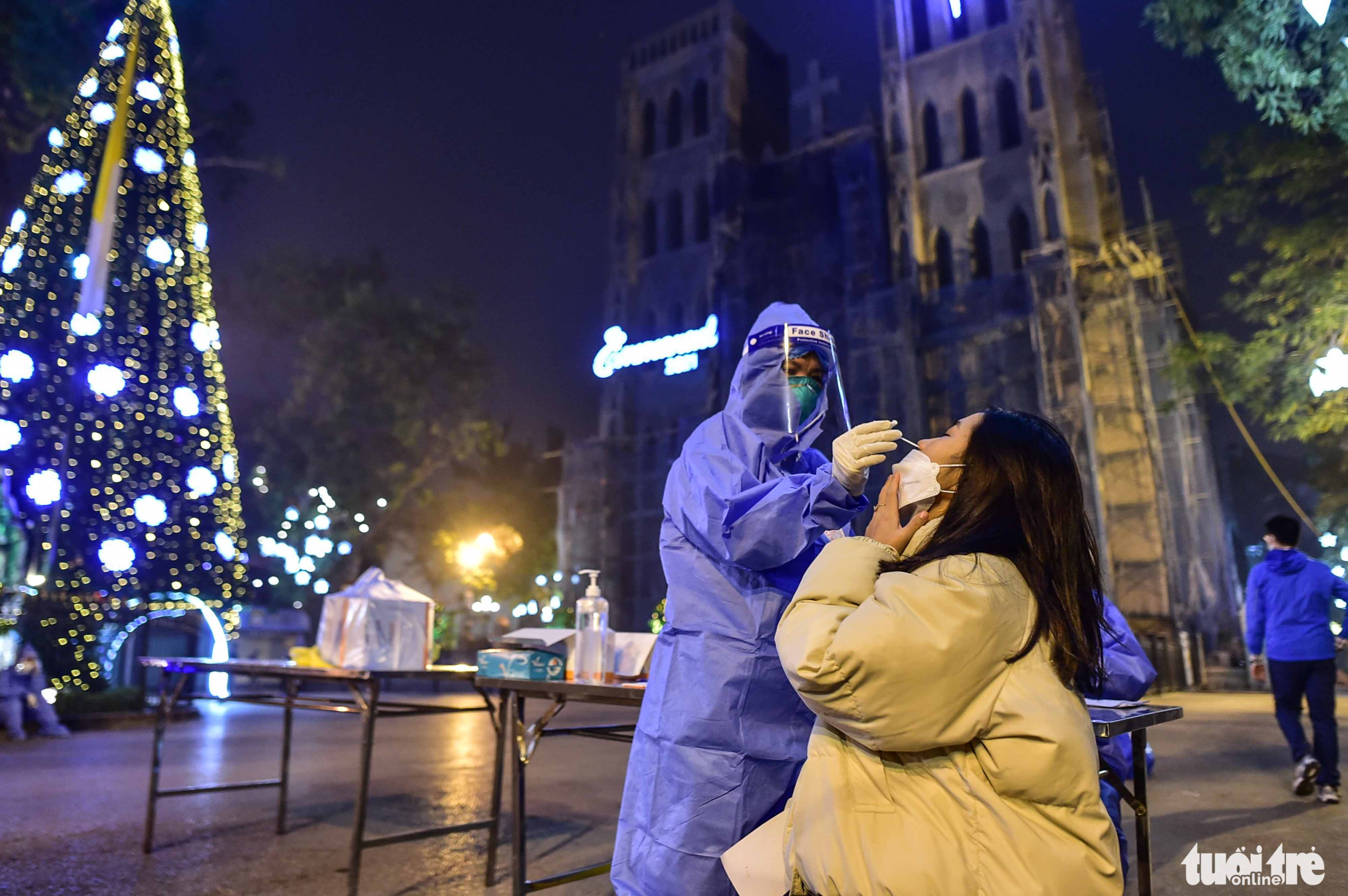A health worker takes a nasal swab from a visitor to the St. Joseph's Cathedral in Hanoi, December 24, 2021. Photo: Dat Quan / Tuoi Tre
