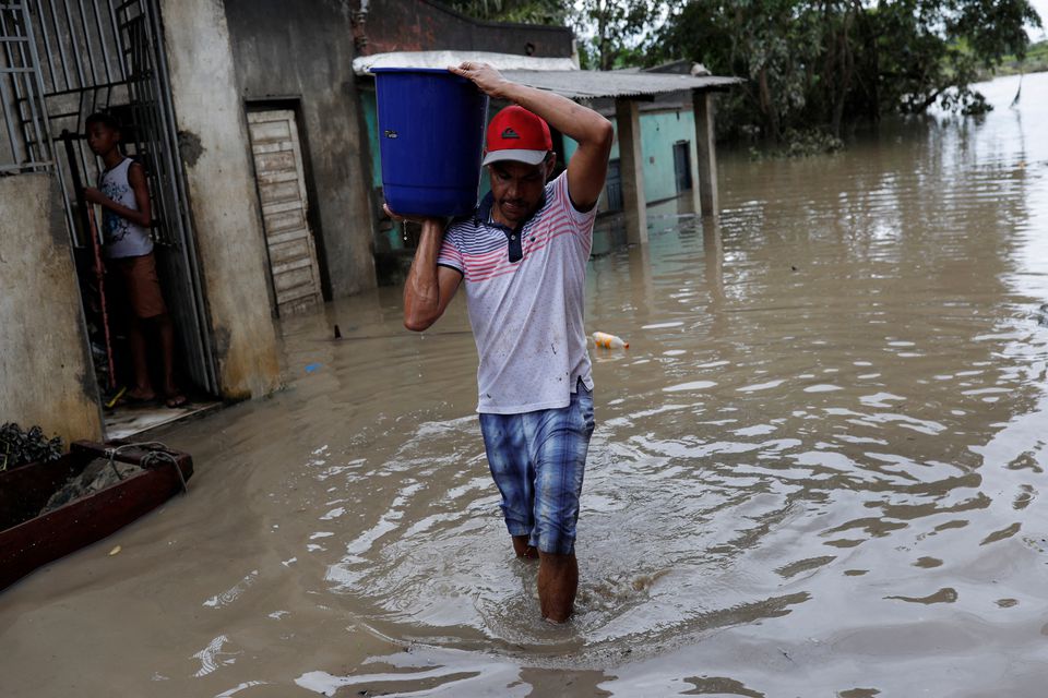 A man carries a bucket of water, during floods caused due to heavy rains, in Itabuna, Bahia state, Brazil December 27, 2021. Photo: Reuters