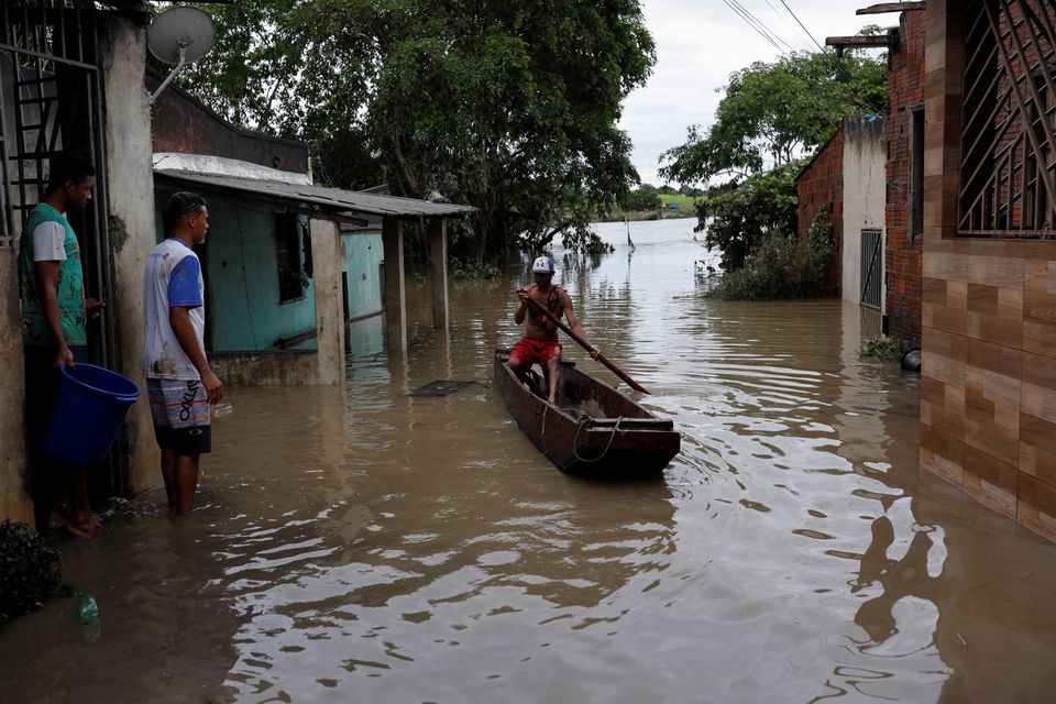 A man paddles a canoe along a street, during floods caused due to heavy rains, in Itabuna, Bahia state, Brazil December 27, 2021. Photo: Reuters
