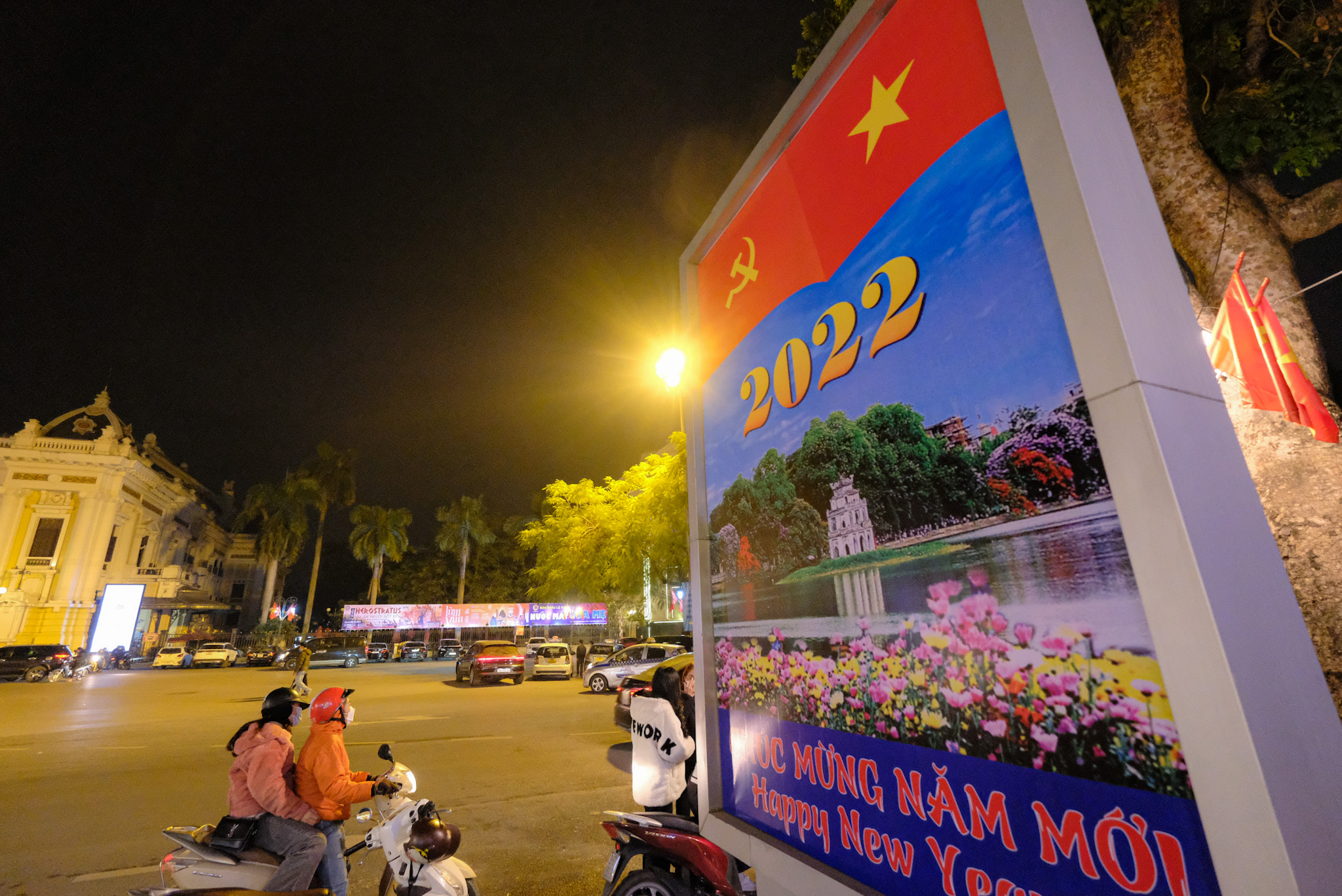 A motorbike goes past a 'Happy New Year' board in front of the Hanoi Opera House in Hanoi on the night of December 31, 2021. Photo: Tuoi Tre