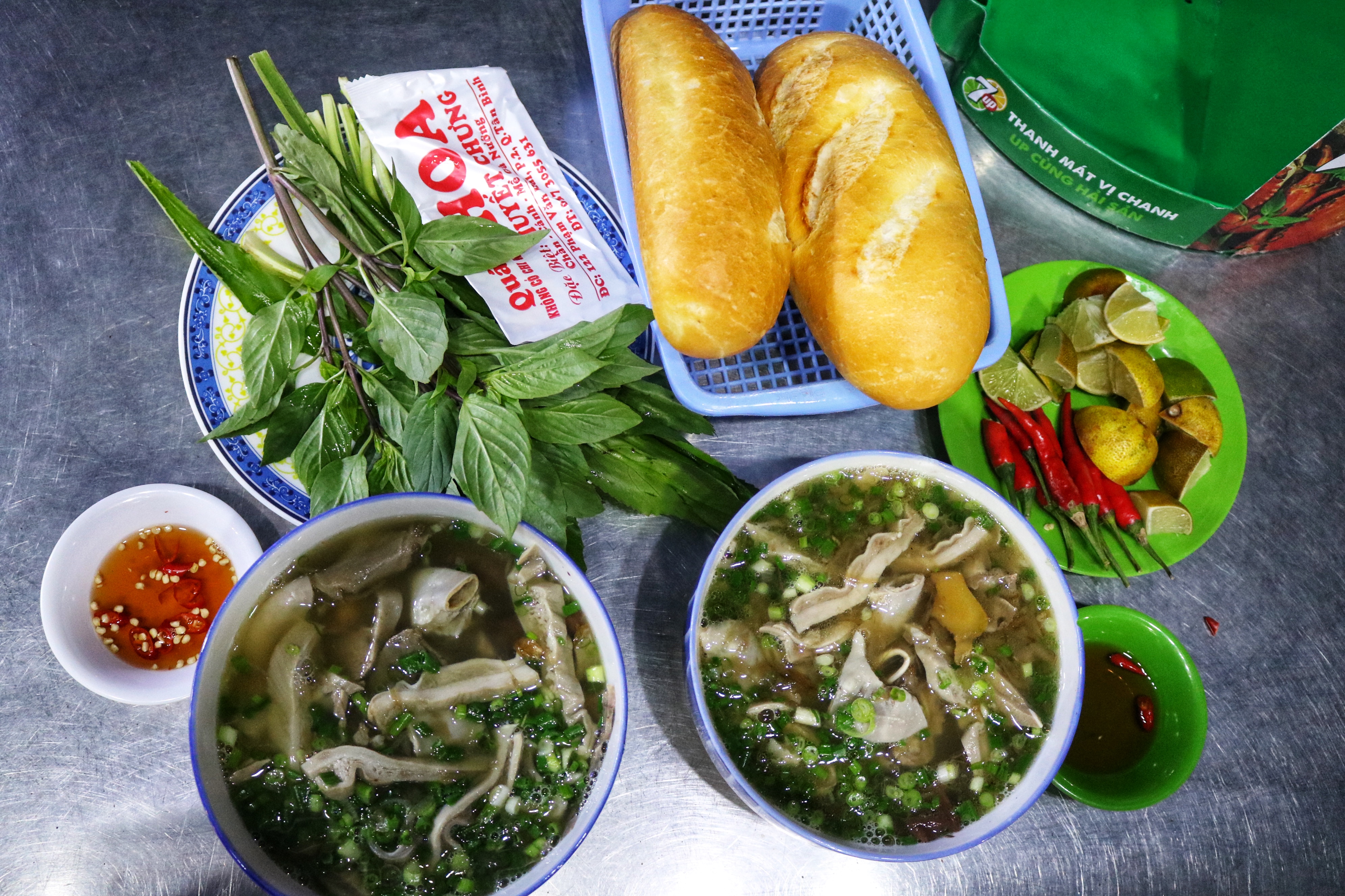 Two bowls of huyet chung, which consists of steamed pig blood pudding topped with organs, are served with bread and herbs at Pham Thi Hoa’s stall on Pham Van Hai Street in Tan Binh District, Ho Chi Minh City. Photo: Hoang An / Tuoi Tre News