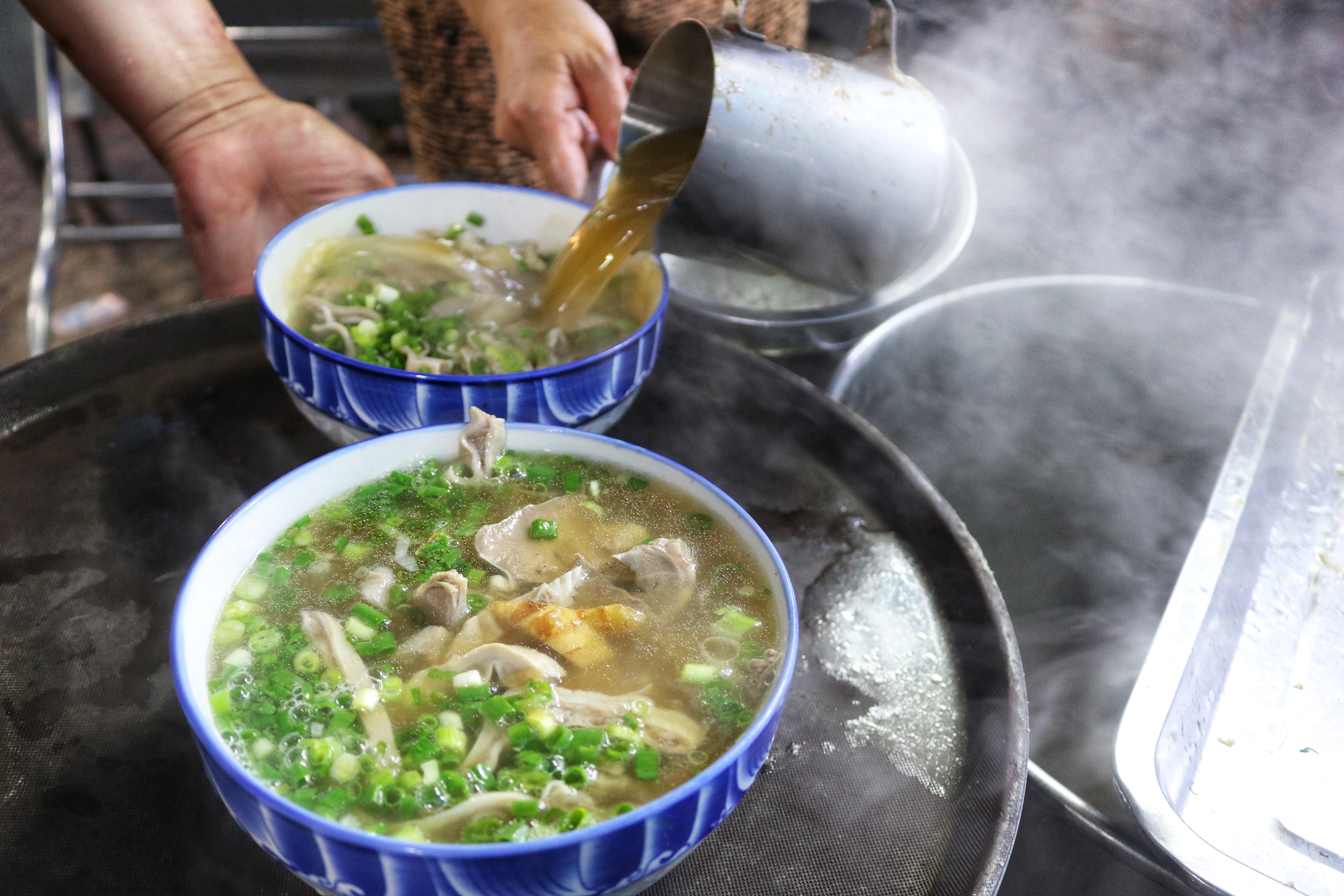 Hoa pours boiling hot broth into bowls of huyet chung at her stall on Pham Van Hai Street in Tan Binh District, Ho Chi Minh City. Photo: Hoang An / Tuoi Tre News