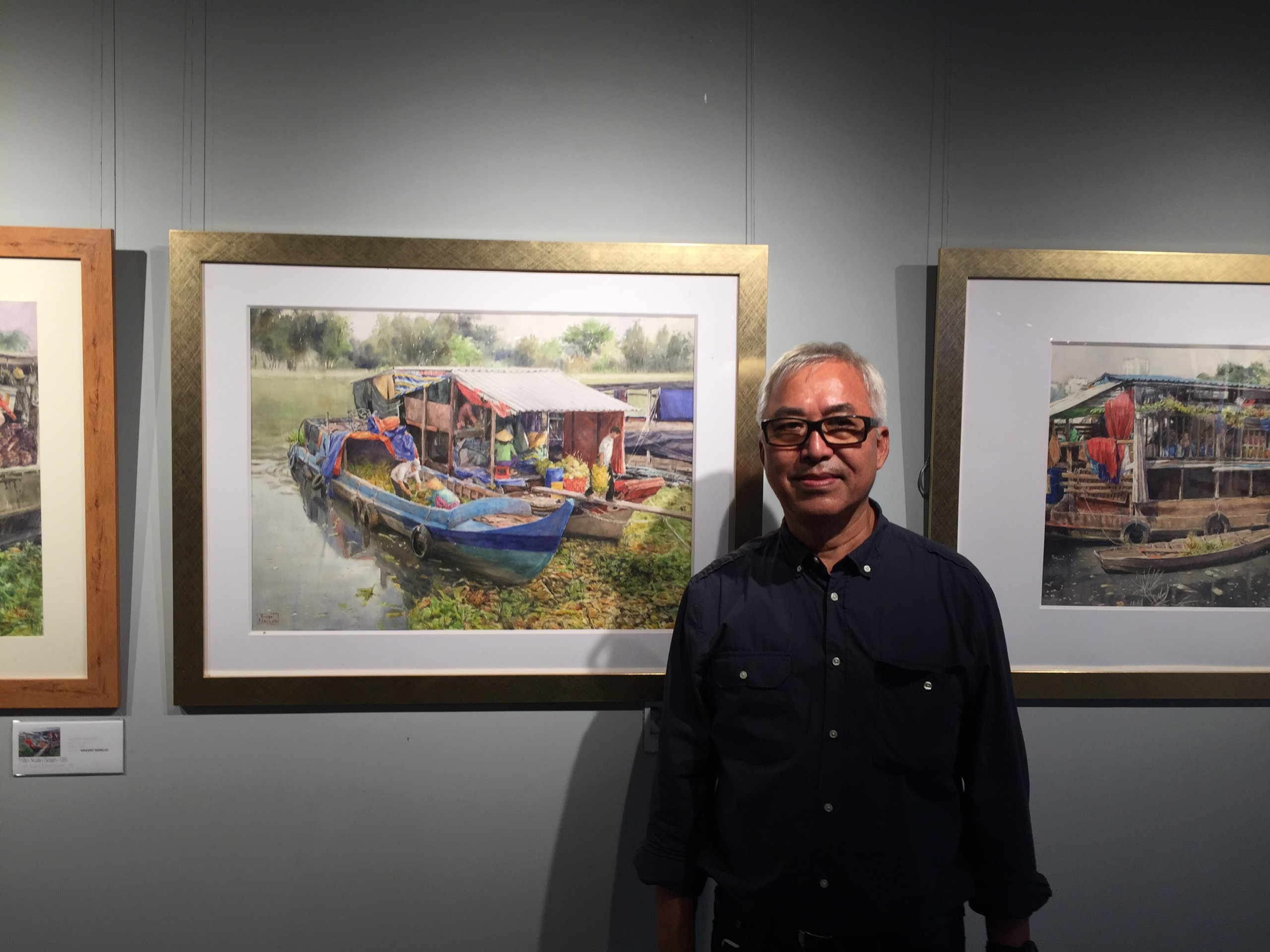 French artist Vincent Monluc is pictured next to his paintings. Photo: Mai Thuy / Tuoi Tre