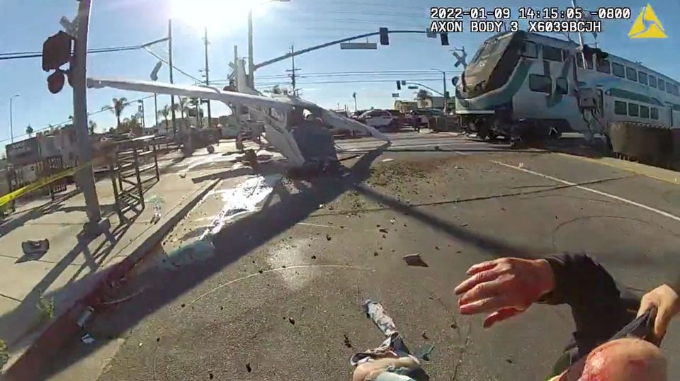 A screen grab from a police body camera video shows the pilot of a plane that crashed on railway tracks being rescued by Los Angeles Police Department officers moments before a train hit the aircraft in Los Angeles, California, U.S. January 9, 2022. LAPD/Handout via Reuters