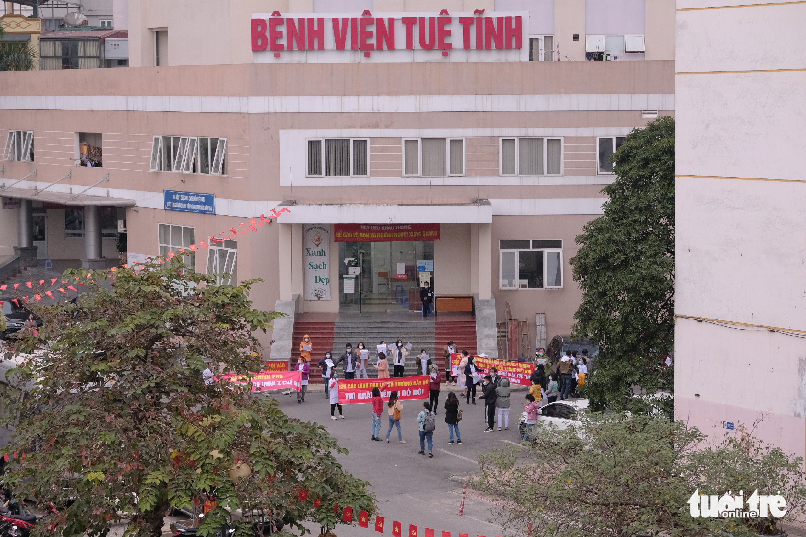 Medical staff hold banners in front of Tue Tinh Hospital to demand their unpaid salaries in Hanoi, January 12, 2022. Photo: Nam Tran / Tuoi Tre