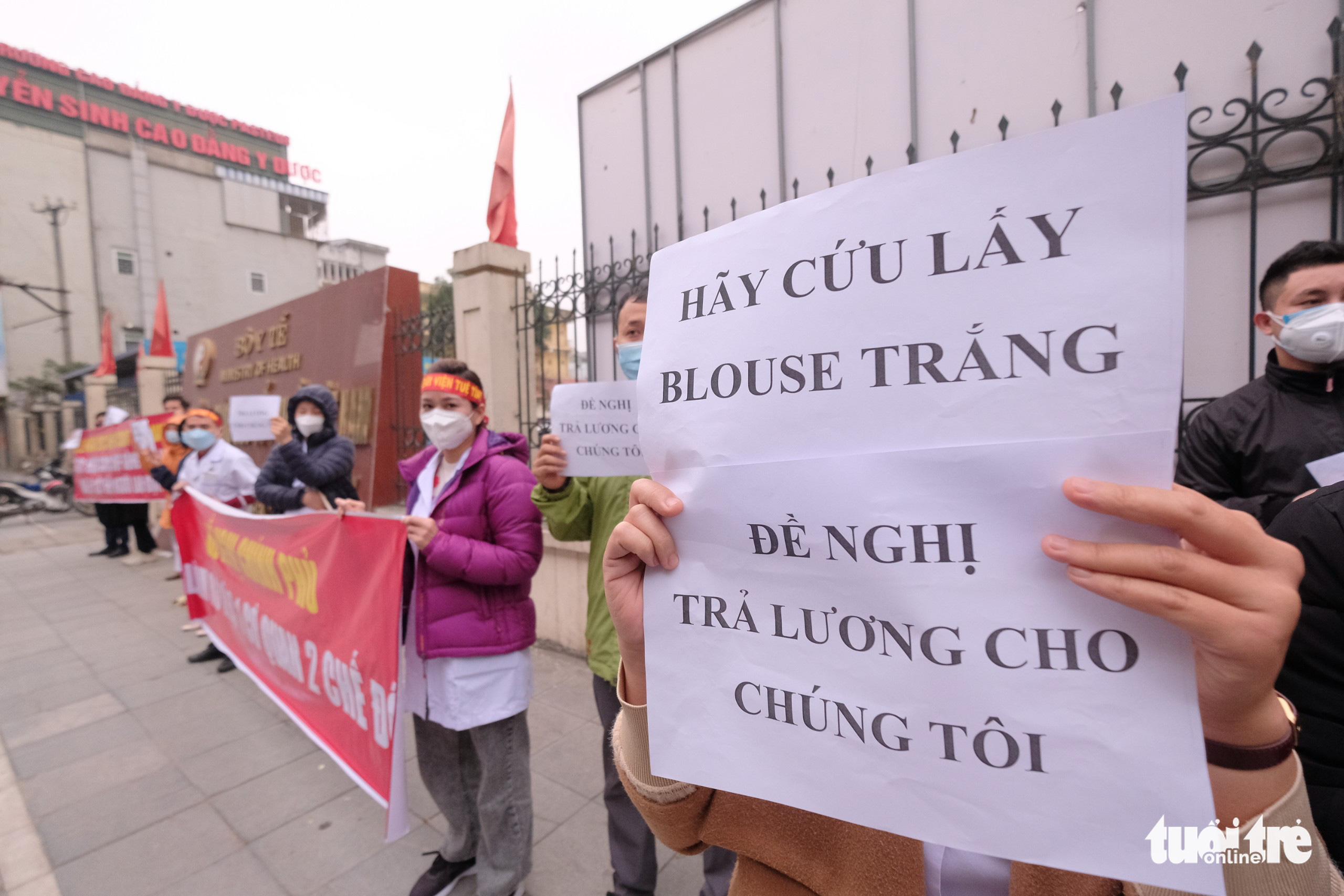 Medical staff hold banners in front of Tue Tinh Hospital to demand their unpaid salaries in Hanoi, January 12, 2022. Photo: Nam Tran / Tuoi Tre
