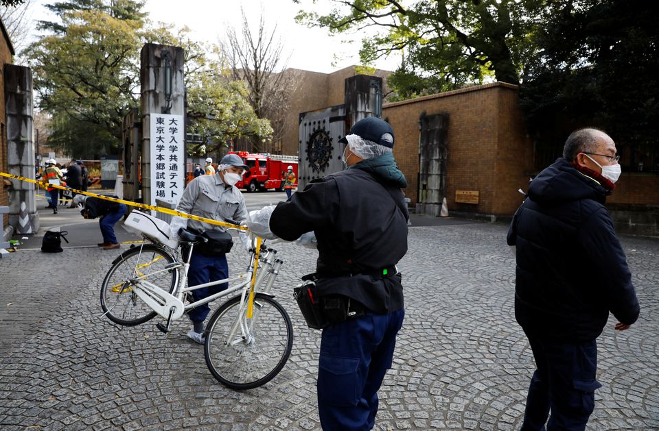 A man moves a bicycle as police officers inspect the site where a stabbing incident happened at an entrance gate of Tokyo University in Tokyo, Japan January 15, 2022. Photo: Reuters