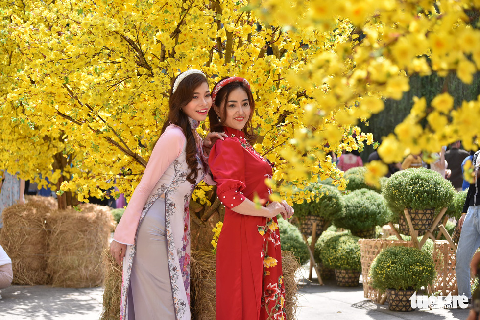 Two women pose for a photo with a yellow apricot background at the Youth Culture House in District 1, Ho Chi Minh City. Photo: Ngoc Phuong / Tuoi Tre