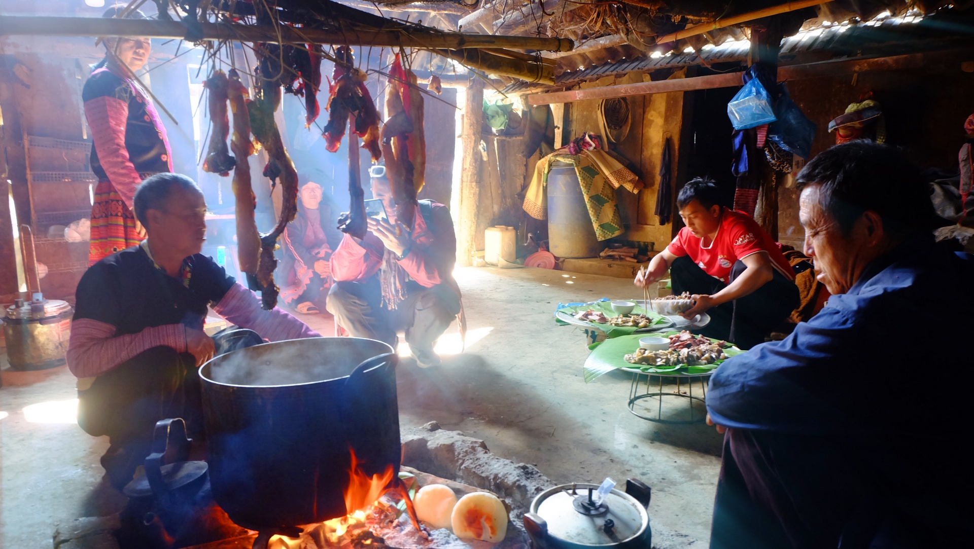 Pieces of pork hung over a burning coal stove, with slightly burned banh day – a traditional rice cake – nearby.